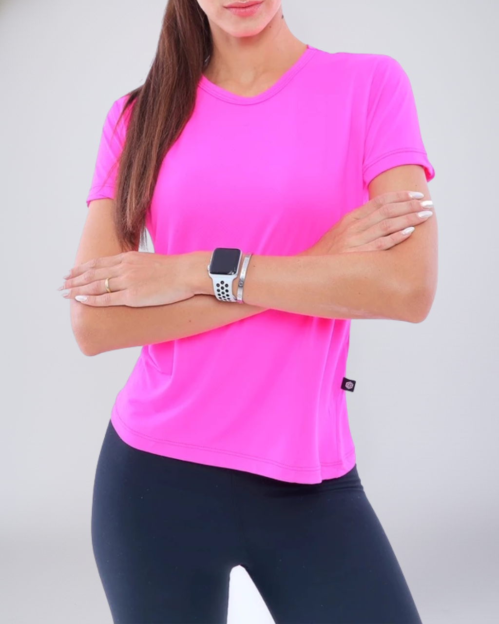 Modelo usando Camiseta Baby Look Dry Fit rosa neon. Peça vibrante e de alta visibilidade, perfeita para corrida noturna e treinos cheios de estilo. Máximo desempenho e respirabilidade