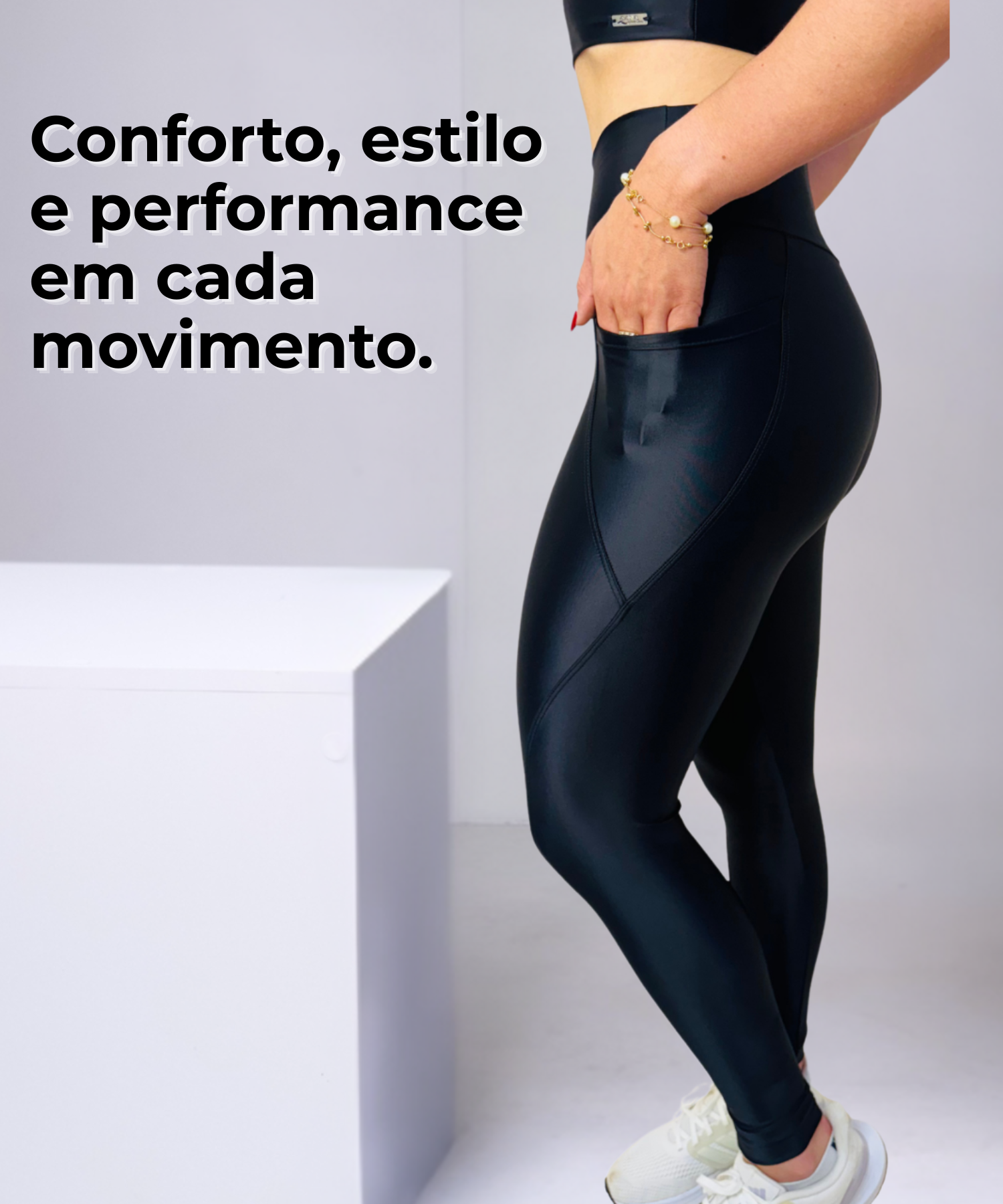 Close-up detalhado de uma legging fitness preta, confeccionada em tecido de alta compressão e brilho sutil. O foco está no bolso lateral funcional, perfeito para celular ou chaves, evidenciando a praticidade e o design moderno da peça da marca ELITE WEAR, ideal para treinos e uso diário com foco em conforto e performance.