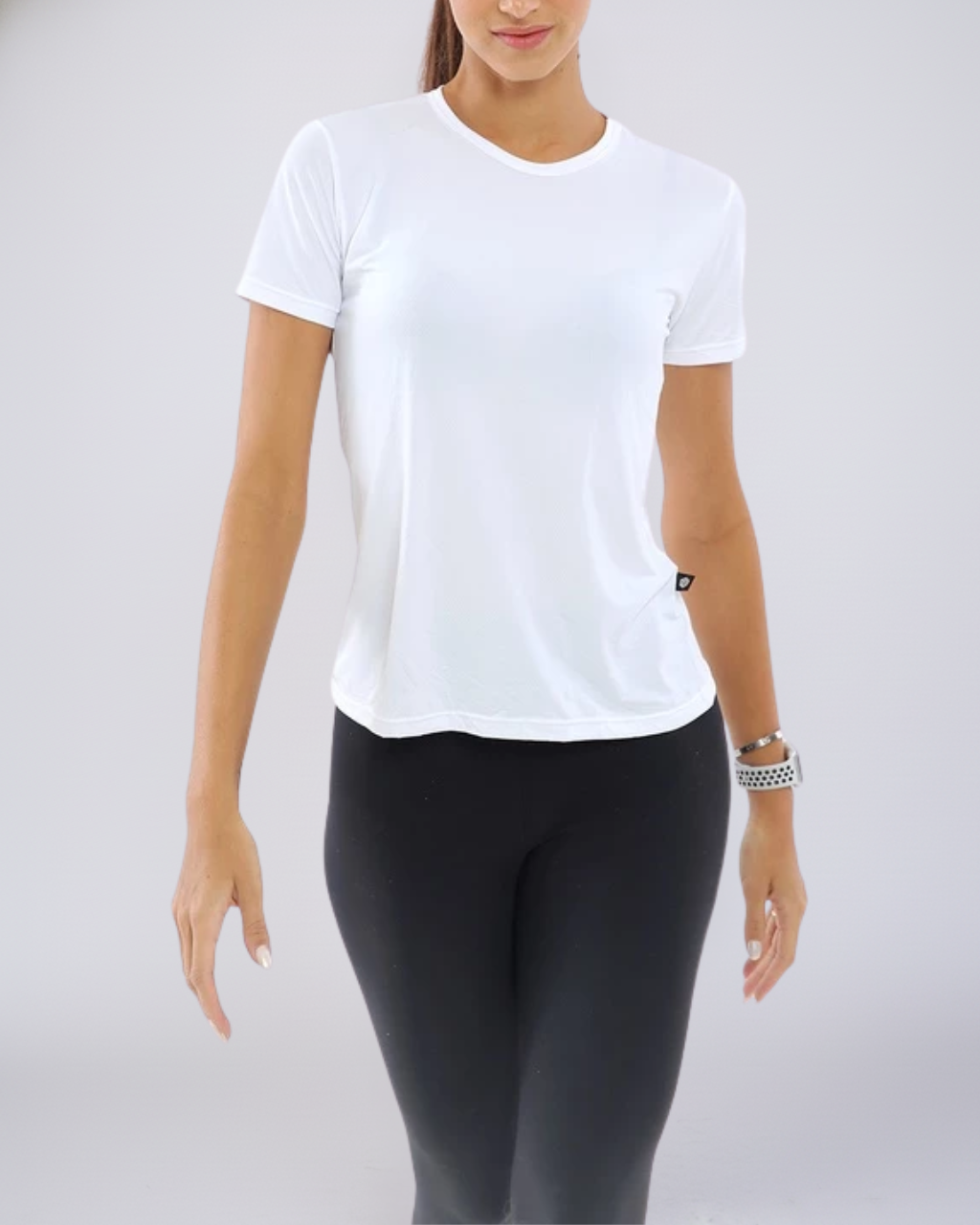 Modelo usando Camiseta Baby Look Dry Fit branca. Design clássico e tecnológico com proteção UV, perfeita para corrida e atividades de alto impacto.