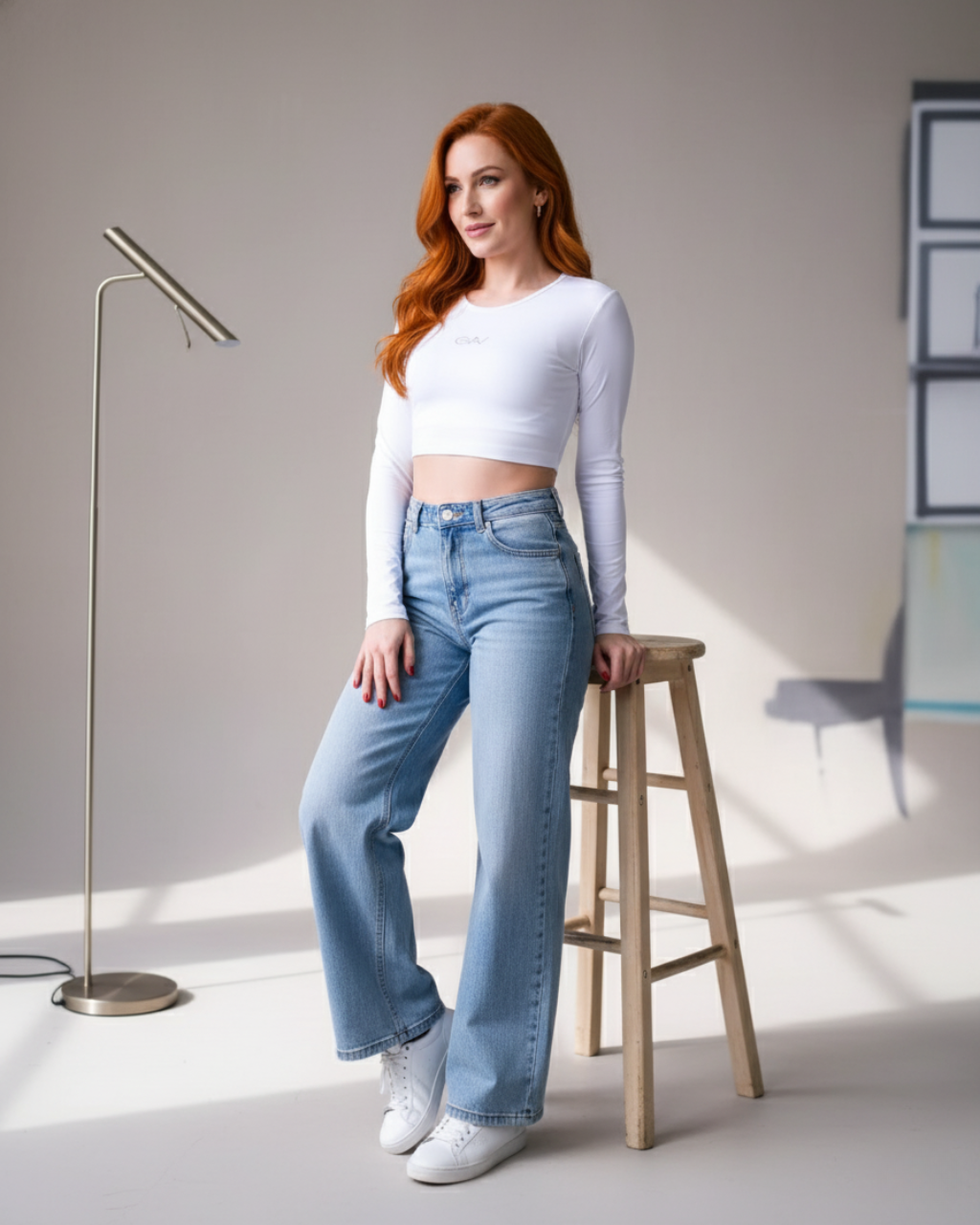 Modelo ruiva em um top cropped canelado branco de manga longa GAV, calças jeans largas de cintura alta e tênis brancos. Look casual e moderno para o dia a dia. Ideal para moda feminina, look fitness e casual.